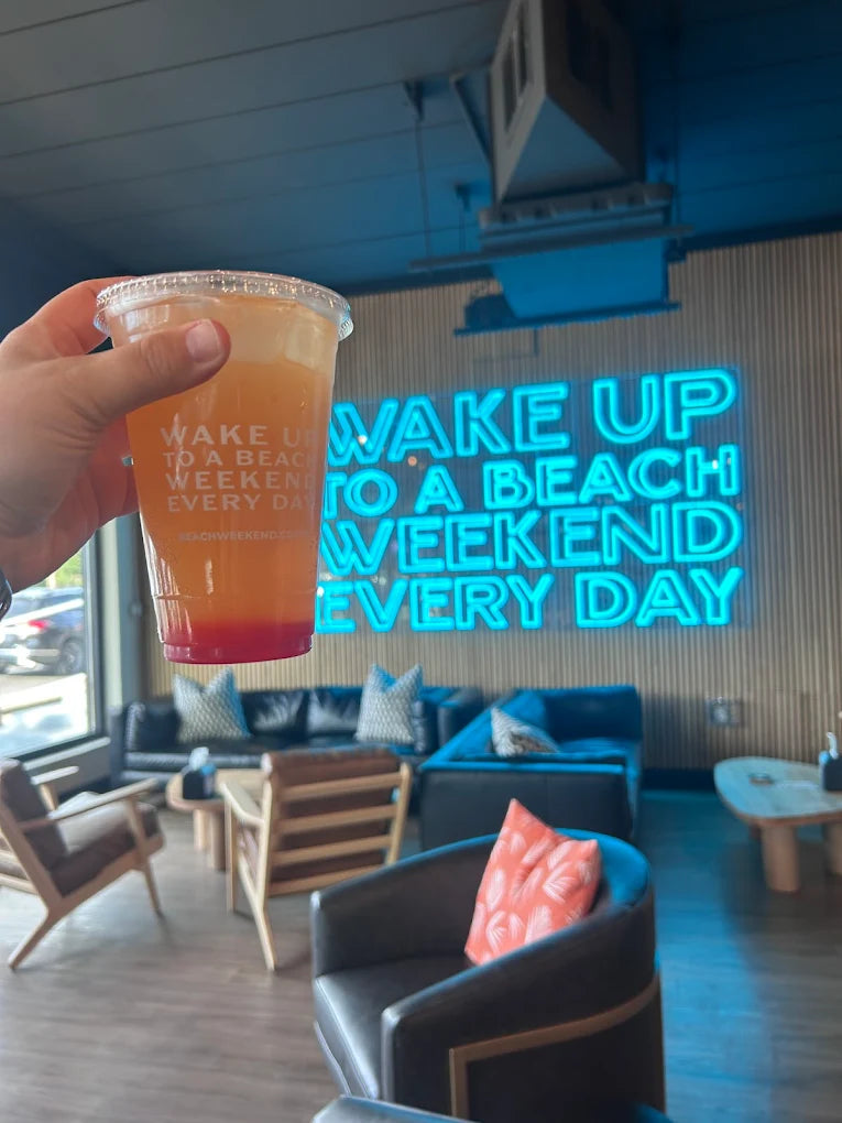 Iced coffee in front of the Beach Weekend neon sign